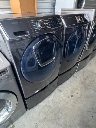 Black stainless front load Samsung washer and dryer with pedestals
