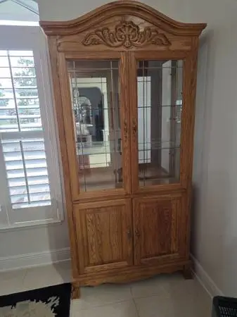 Elegant wooden display cabinet with glass doors and shelves.