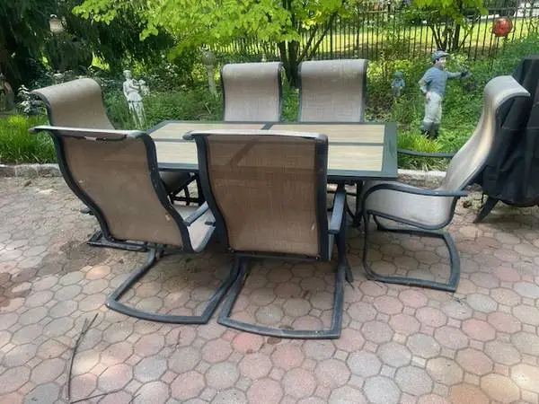 Dark bronze tile top patio table with six sling chairs
