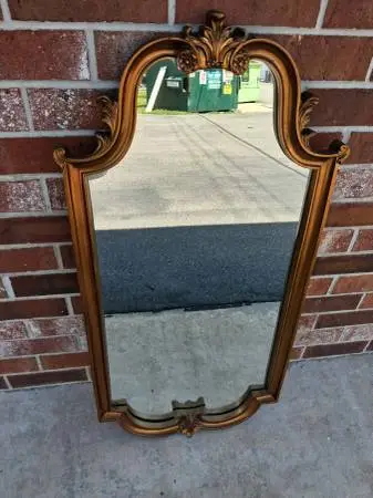 Vintage gold wall mirror has an ornate scroll design.