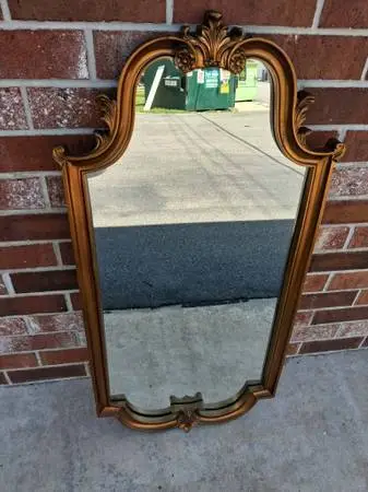 Vintage gold wall mirror has an ornate scroll design.