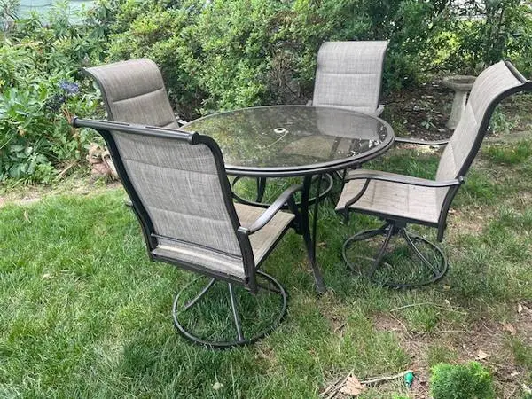Dark bronze finish glass top round patio table and four sling chairs