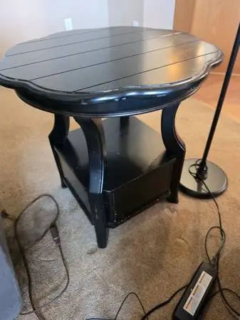 Black scalloped end table with lower shelf and drawer.