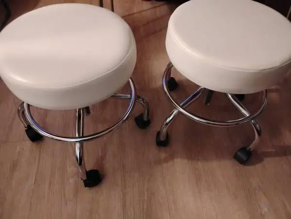 2 white cushion stools on wheels