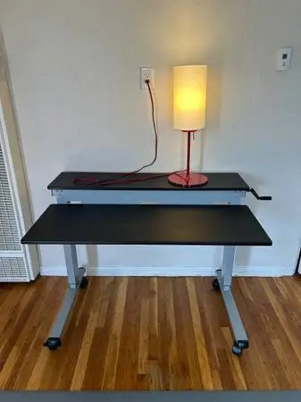 Sit-stand office desk with two tier surface and locking casters