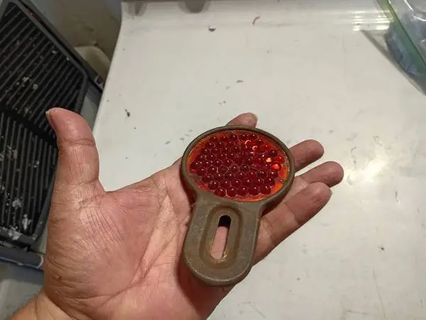 old red glass safety reflector has cracks and chips from age patina