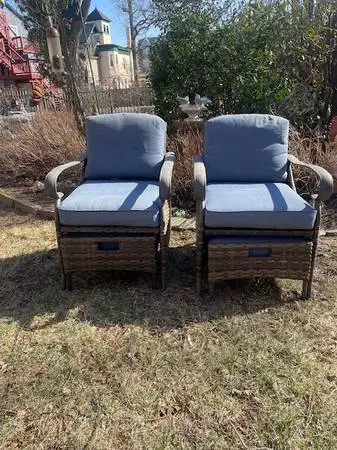 Pair of faux wicker and steel patio chairs with ottomans